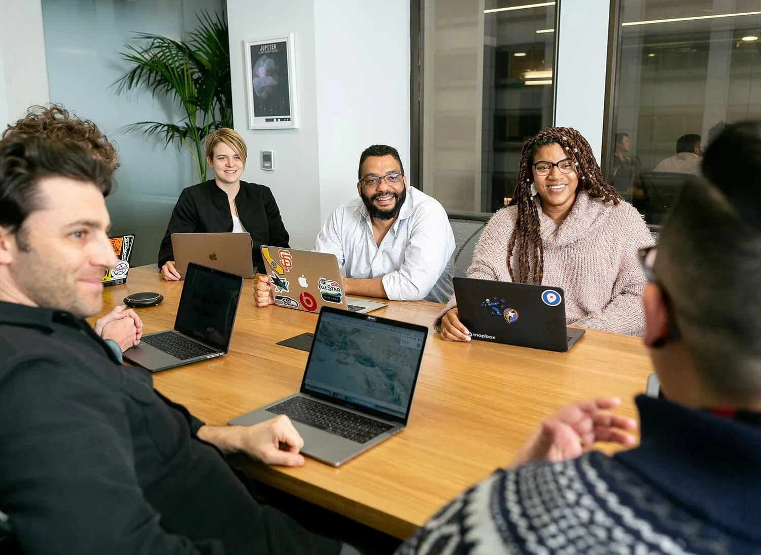 Diverse leadership team in financial strategy meeting around a table with laptops