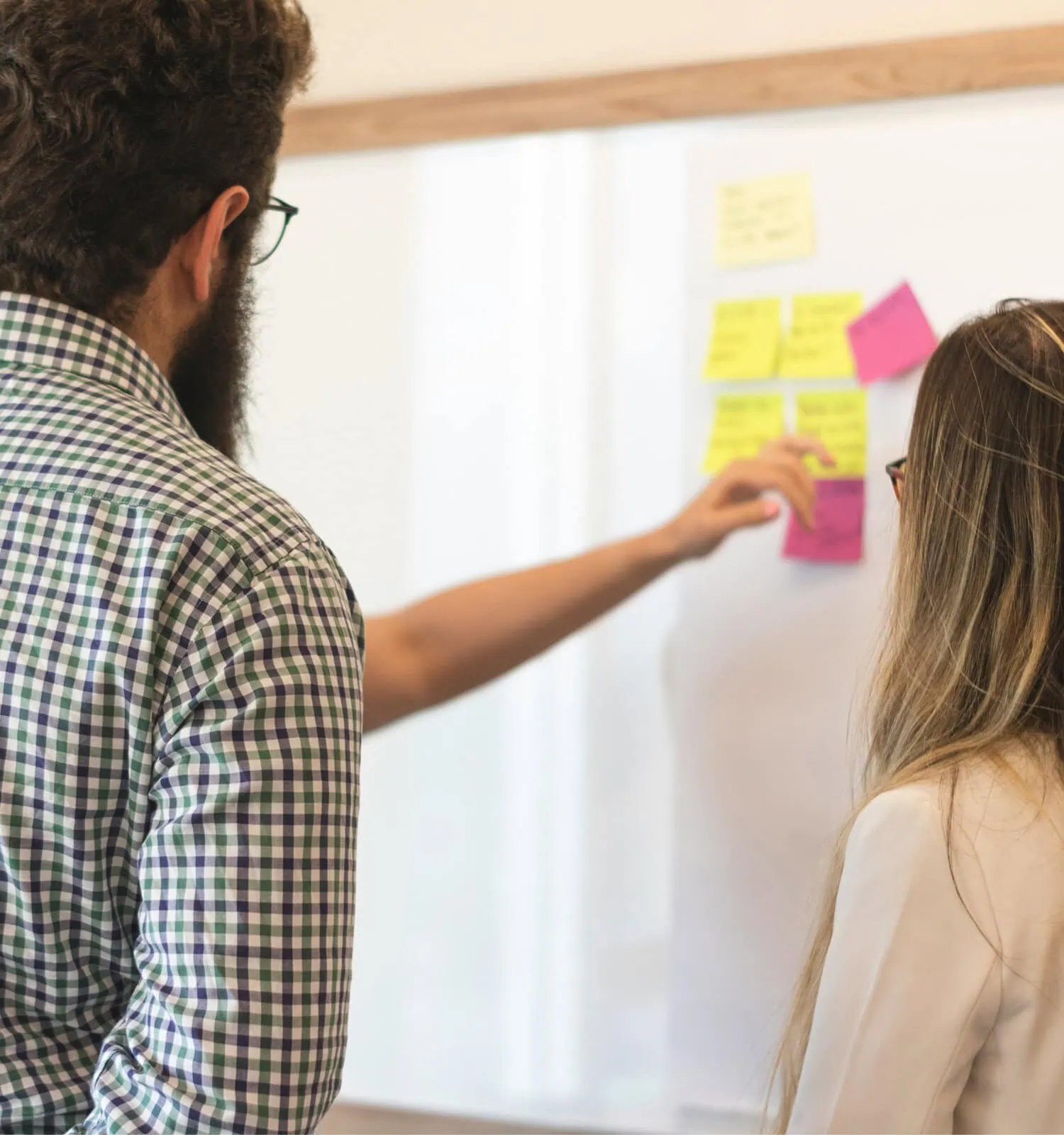 Business consultants mapping strategy with sticky notes on a whiteboard